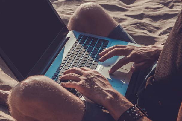 Молодой человек работает за ноутбуком на пляже. Дауншифтинг
 - Фото, изображение