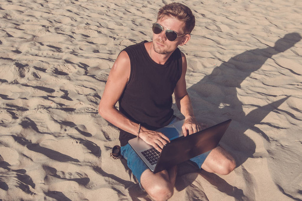 Jonge man werken op laptopcomputer op het strand. Terugschakelen - Foto, afbeelding