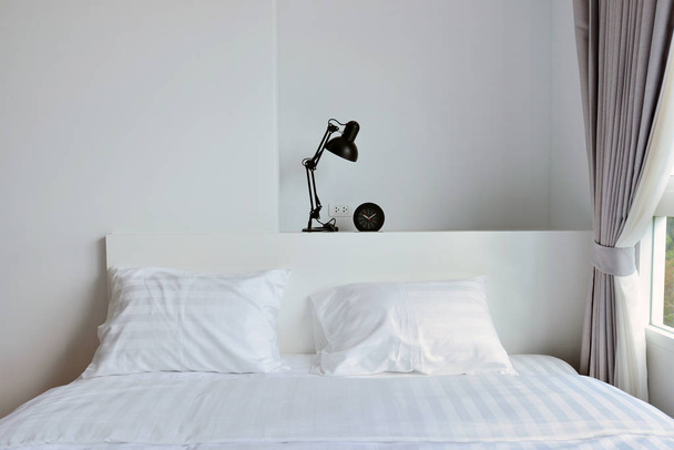 сучасна лампа на дерев'яній підставці в білій сучасній спальні, інтер'єр
 - Фото, зображення