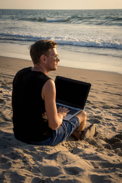 Genç adam sahilde dizüstü bilgisayar üzerinde çalışıyoruz. Ucu - Fotoğraf, Görsel