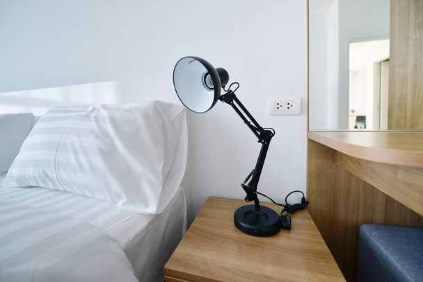 moderne lamp op houten nachtkastje in witte moderne slaapkamer, interi - Foto, afbeelding