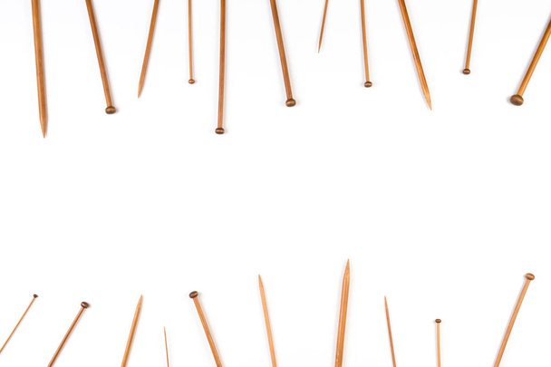 Aiguilles à tricoter en bambou en bois disposées comme bordure du cadre sur fond blanc
 - Photo, image