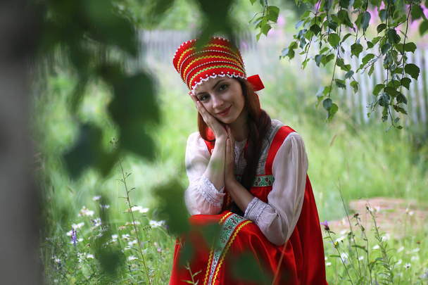 Слов'янська в традиційному одязі сидить в природі - Фото, зображення