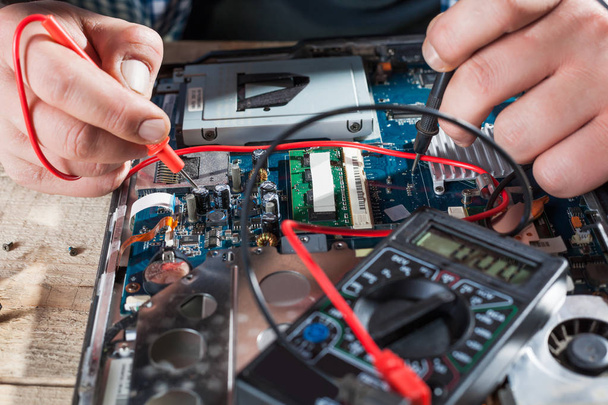 engineer making diagnostics of laptop with multimeter - Foto, Imagem
