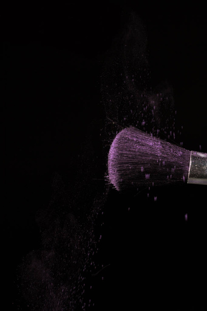 Make up brush with purple dust on black background - Foto, imagen