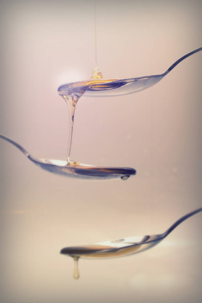 Miele versando da cucchiaio su uno sfondo leggero
 - Foto, immagini