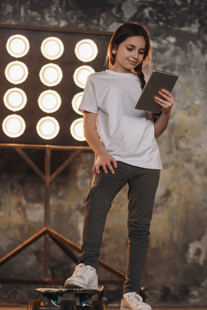 Little girl with skateboard and tablet - Φωτογραφία, εικόνα