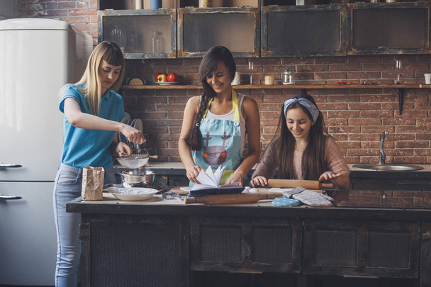Two young women and girl in the kitchen - 写真・画像