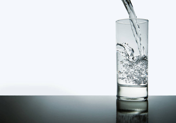 water spatten van glas met copyspace, geïsoleerd en blauwe toned - Foto, afbeelding