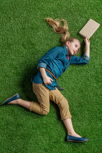 Girl with book lying on grass  - Foto, afbeelding
