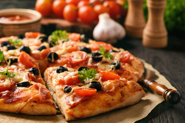 Homemade pizza with ham, cheese, tomatoes and olives. - Valokuva, kuva