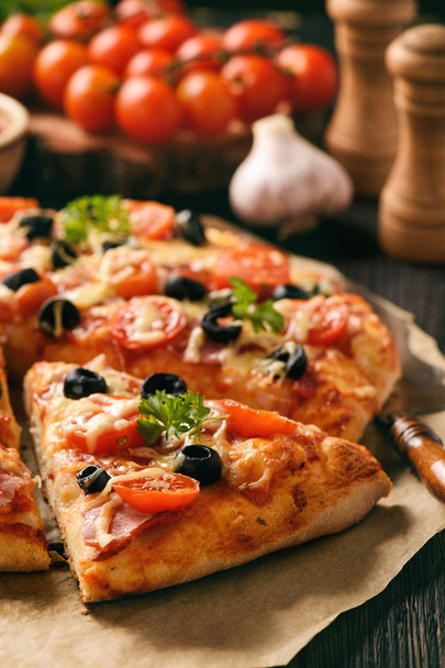 Kotitekoinen pizza kinkulla, juustolla, tomaateilla ja oliiveilla
. - Valokuva, kuva