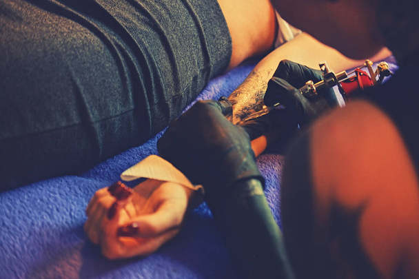 Dokonywanie tatuaż na ramieniu kobiety. - Zdjęcie, obraz