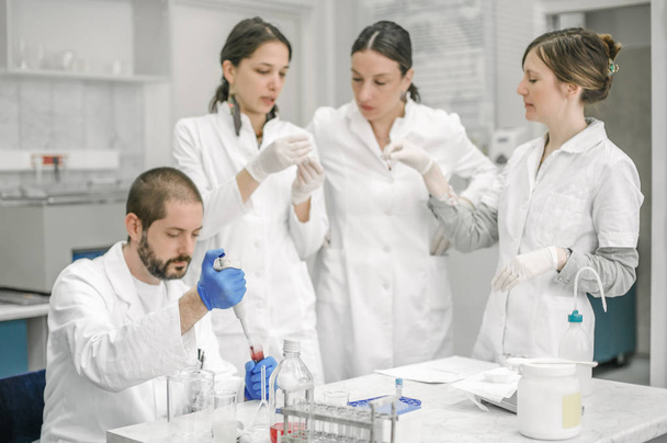 Group of scientists working with liquid test tube samples - Φωτογραφία, εικόνα