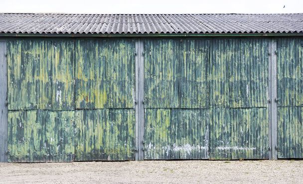 rozsdás hullámos vas ajtó, fészer, zöld és sárga festékkel - Fotó, kép