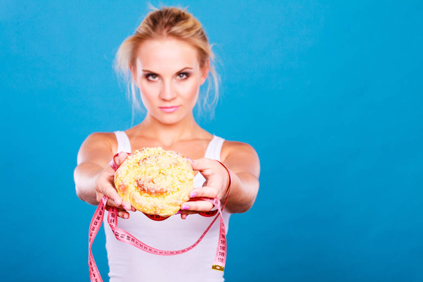 Woman holds sweet bun recommending non sugar diet - Fotografie, Obrázek