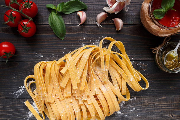 Fresh homemade pasta and vegetables on the dark wooden table top view - Фото, зображення