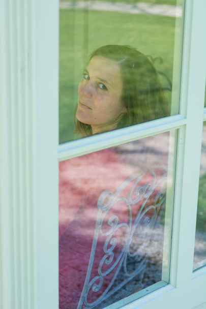 Attractive brunette looking through a window. - Photo, Image