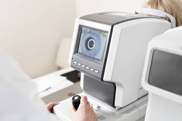 kobiety patrzące na maszynę do badania wzroku w klinice okulistycznej - Zdjęcie, obraz