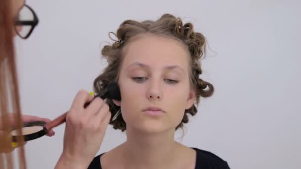 Professional make-up artist applying powder to womans face - Кадри, відео