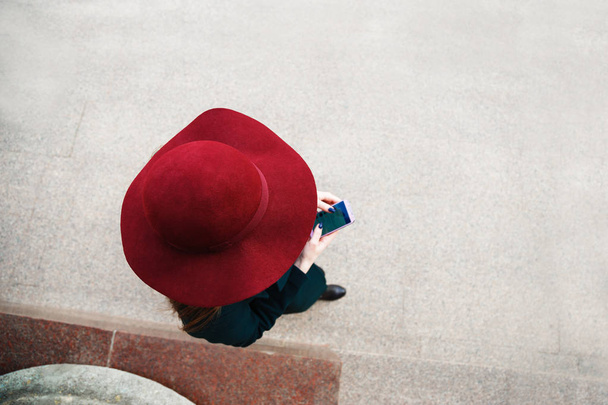 Woman in hat strolls around the city and uses her mobile phone. View from above - Photo, Image