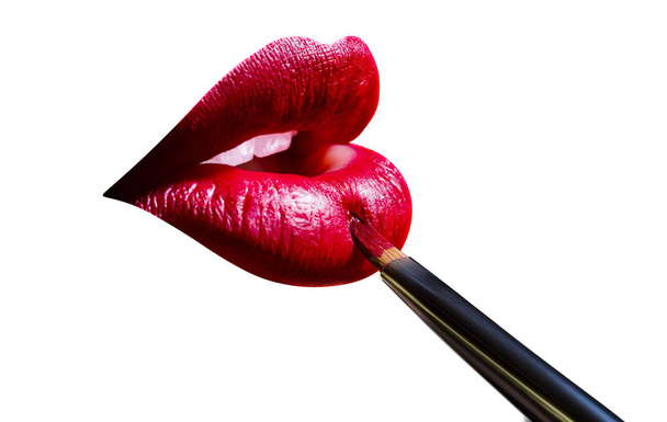 Lápiz labial y pincel para pintalabios en los labios de las mujeres sexy. Lápiz labial rojo en los labios llenos regordetes. Atractiva y sensual boca de mujer con maquillaje. Muchacha sonriente al aplicar maquillaje en sus labios aislados
 - Foto, Imagen