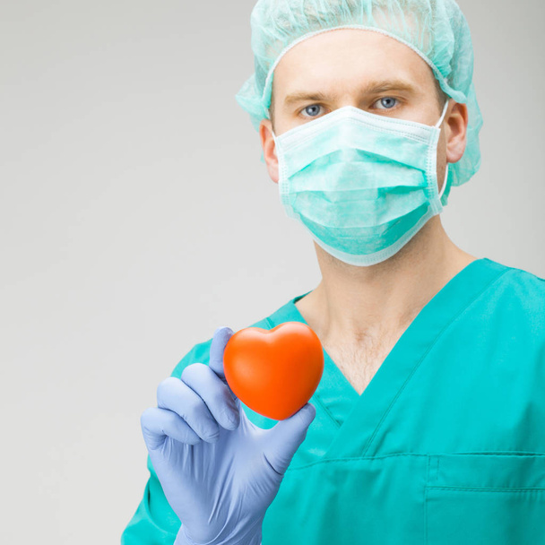 Surgeon holding toy heart with one hand - medicine and healthcare symbols - Foto, immagini