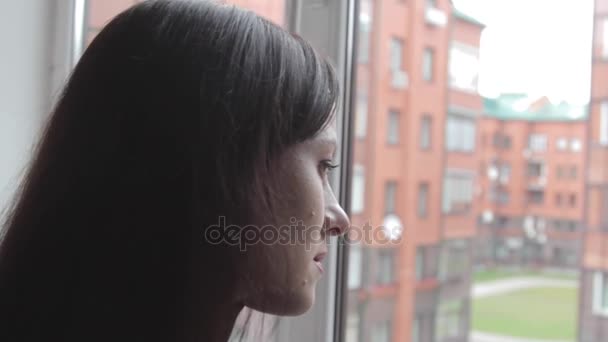Dívka vypadá zamyšleně z okna - Záběry, video