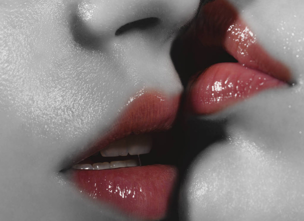 Lesbian kiss, black and white face with pink lipstick and lip gloss. Passion and sex. Homosexual sex. Girl is kissing her girlfriend. Women's love and passion. Female tenderness and relationships - Photo, Image