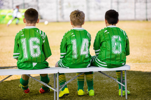 Lasten jalkapallojoukkue. Young Boys Reserve Pelaajat istuvat penkillä ja katsomassa Youth Soccer Match. Koulun jalkapallo jalkapallo peli
 - Valokuva, kuva