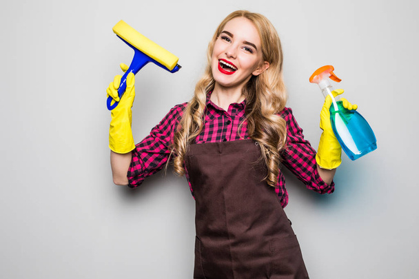 Happy young woman cleaning windows isolated over grey background - Φωτογραφία, εικόνα