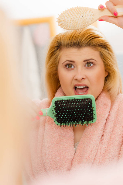 Shocked woman wearing dressing gown brushing her hair - Photo, Image