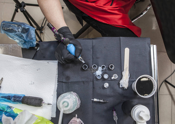 Tetováló művész asztalt, miközben ő az újratöltése a fegyvert - Fotó, kép