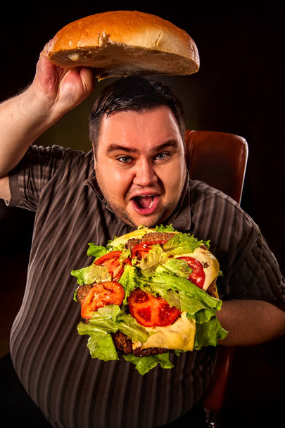 Fat man eating fast food hamberger. Breakfast for overweight person. - 写真・画像
