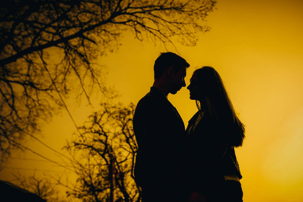 Amazing silhouette of lovers. True love emotions of joyful cute couple enjoying time together outdoor in city. Lovely happy moments, having fun, smiling in love on the background of the city. - Foto, immagini