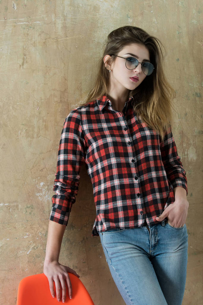 Pretty girl in glasses wearing red plaid shirt and jeans - Foto, imagen