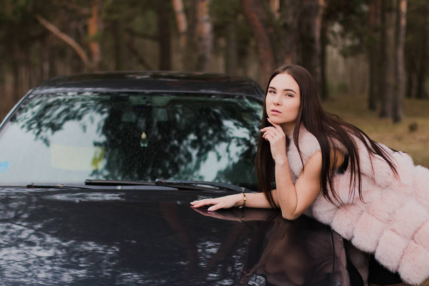 Portret van een heel mooi meisje in een forest gekleed in bont in een auto - Foto, afbeelding