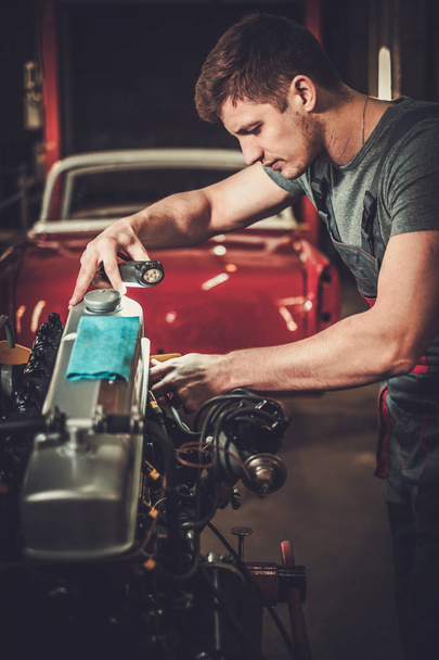 Mecánico trabajando en motor de coche clásico en taller de restauración
 - Foto, imagen