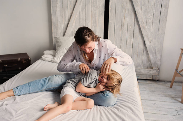mother playing with child son in the morning on bed. Happy family spending weekend at home - Fotoğraf, Görsel