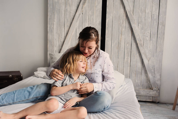 Mutter spielt morgens mit Kind Sohn im Bett glückliche Familie verbringt Wochenende zu Hause - Foto, Bild