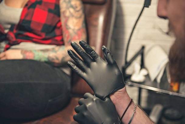 Man wearing gloves before creating picure on female body - Valokuva, kuva