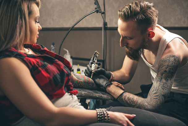 Serene man making tattoo on woman hand - Zdjęcie, obraz
