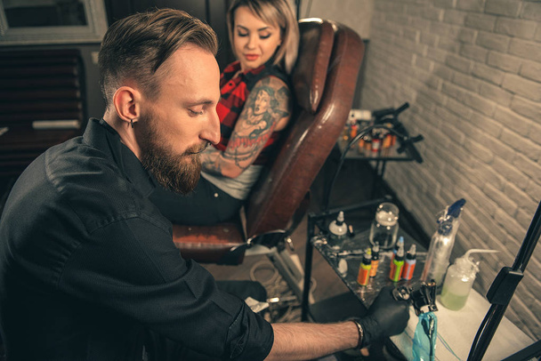 Calm male master putting color in tattoo machine - Fotoğraf, Görsel