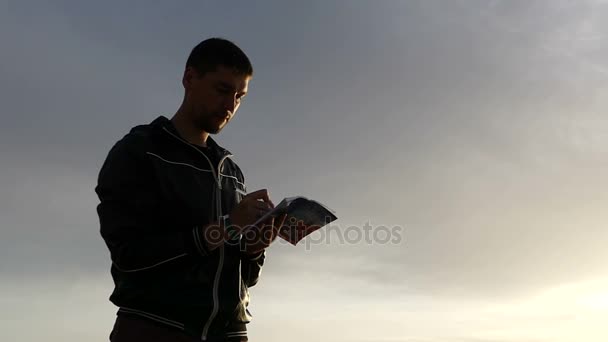 Szép látszó naplemente és egy sziluett egy ember írás le valamit a Notebook. - Felvétel, videó