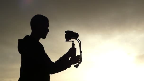 herrlicher Sonnenuntergang und die Silhouette eines Kameramanns, der ein Video dreht. - Filmmaterial, Video