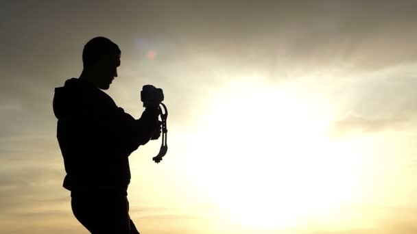 Filmemachen bei Sonnenuntergang - Mann mit stetiger Kamera macht Video. - Filmmaterial, Video