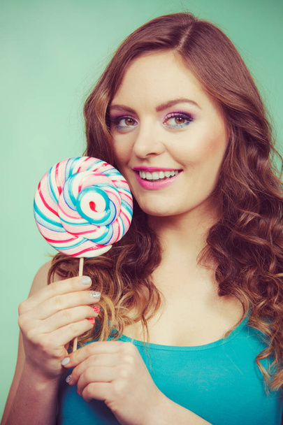 Smiling girl with lollipop candy on teal - Fotó, kép