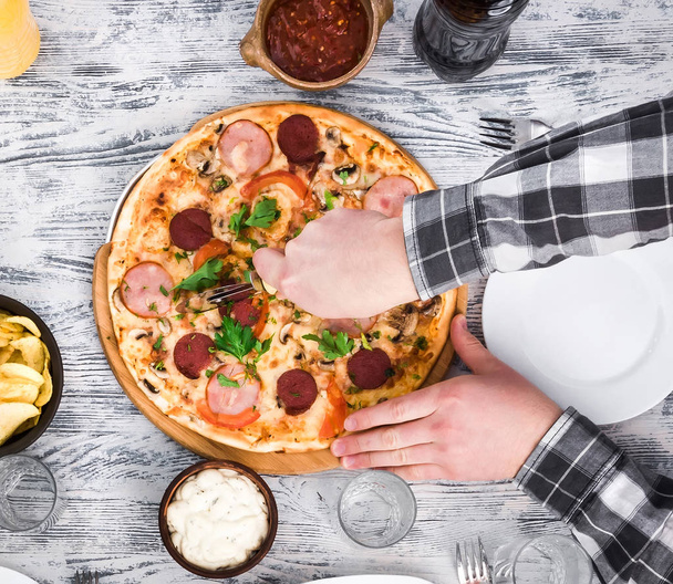 hands cutting pizza on table - Foto, Bild