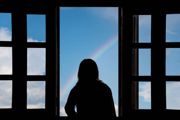 Σιλουέτα νεαρή γυναίκα στο ξενοδοχείο, κοιτάζοντας το μπλε του ουρανού μέσα από ου - Φωτογραφία, εικόνα