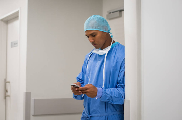 Young doctor using phone - Фото, изображение